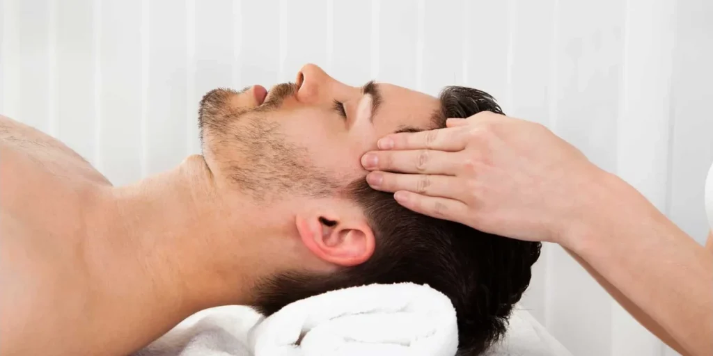 Young man getting a scalp massage as a natural hair loss treatments
