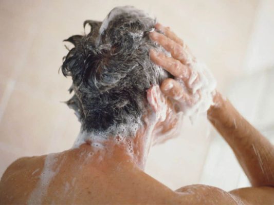 Man using ketoconazole shampoo in the shower to treat hair loss